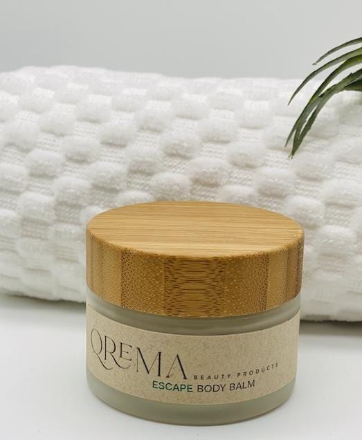 Qrema ESCAPE Body Balm - Qrema Paradise awaits as you escape with our Coconut Lime scented body balm. Wrap yourself in a delightful cocktail of aromas that are sure to take you far, far, away. Escape has properties that help soothe, relax. It's uplifting and invigorating. It can help clear your mind and encourage mental energy. Ingredients: shea butter, mineral oils, fragrance essential oil and natural powder. *Contains Tree Nuts 2 oz container with a bamboo lid.