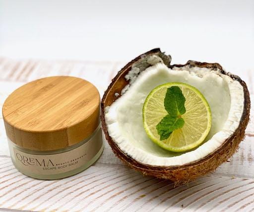 Qrema ESCAPE Body Balm - Qrema Paradise awaits as you escape with our Coconut Lime scented body balm. Wrap yourself in a delightful cocktail of aromas that are sure to take you far, far, away.  Escape has properties that help soothe, relax. It's uplifting and invigorating. It can help clear your mind and encourage mental energy.   Ingredients: shea butter, mineral oils, fragrance essential oil and natural powder.  *Contains Tree Nuts   4 oz glass container with bamboo lid.