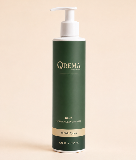 A bottle of QREMA Seda Gentle Cleansing Milk, 190 ml, featuring a dark green label with gold lettering and a white pump dispenser, set against a solid pale peach background.